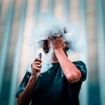 A young man creating vape clouds in an urban setting in Brisbane City, Australia.